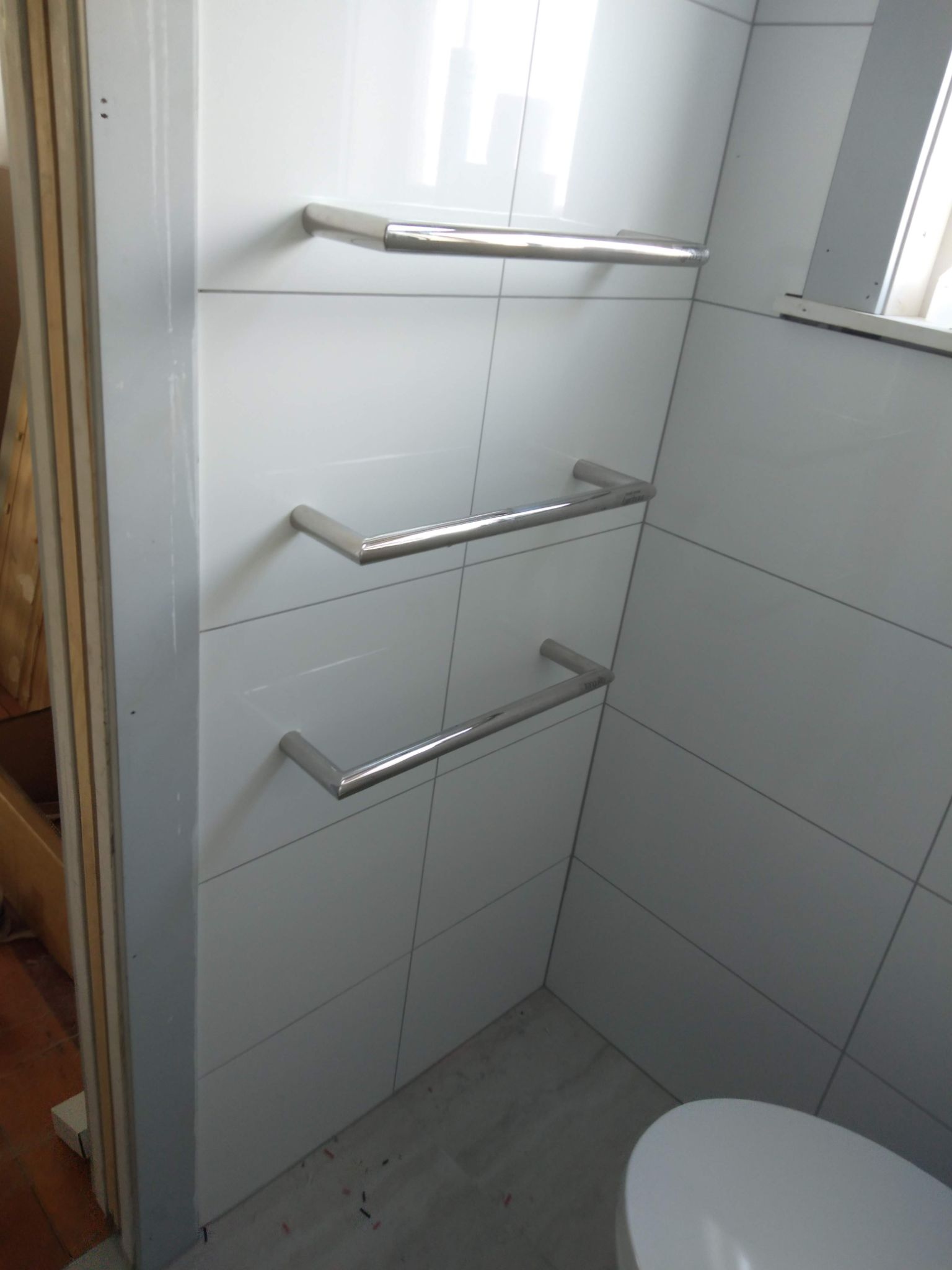 Three heated towel rails on a tiled bathroom wall