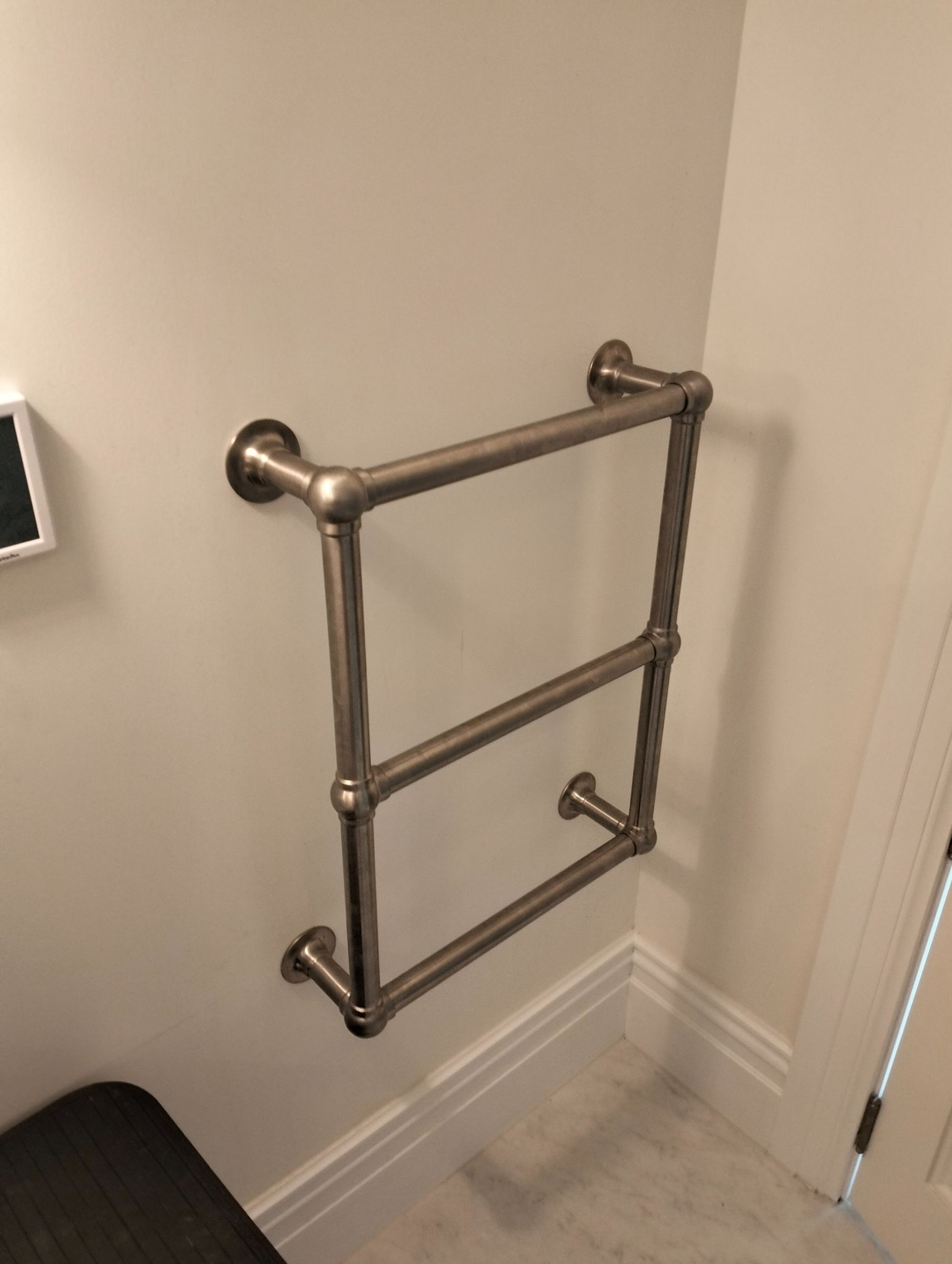 Brushed chrome heated towel rail mounted on a clean white wall